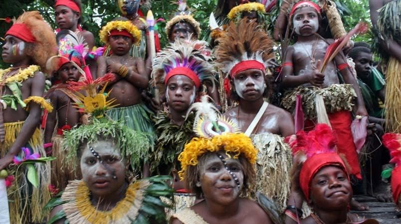 Young people of New Ireland in traditional dress and headdresses at a community gathering